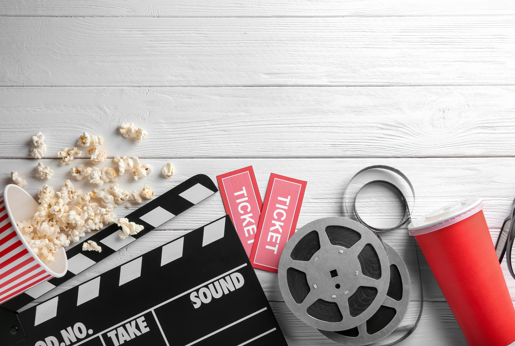 Tasty Popcorn, Movie Reel, Tickets and Clapboard on Wooden Background